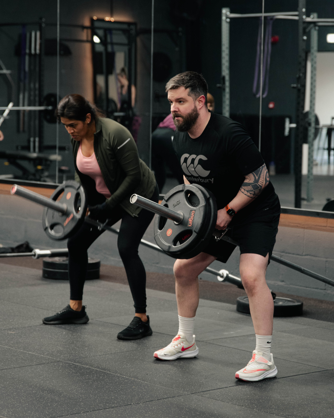Two people enjoying a landmine row workout together in a Gateshead gym, training with guidance in a positive and energetic fitness environment.