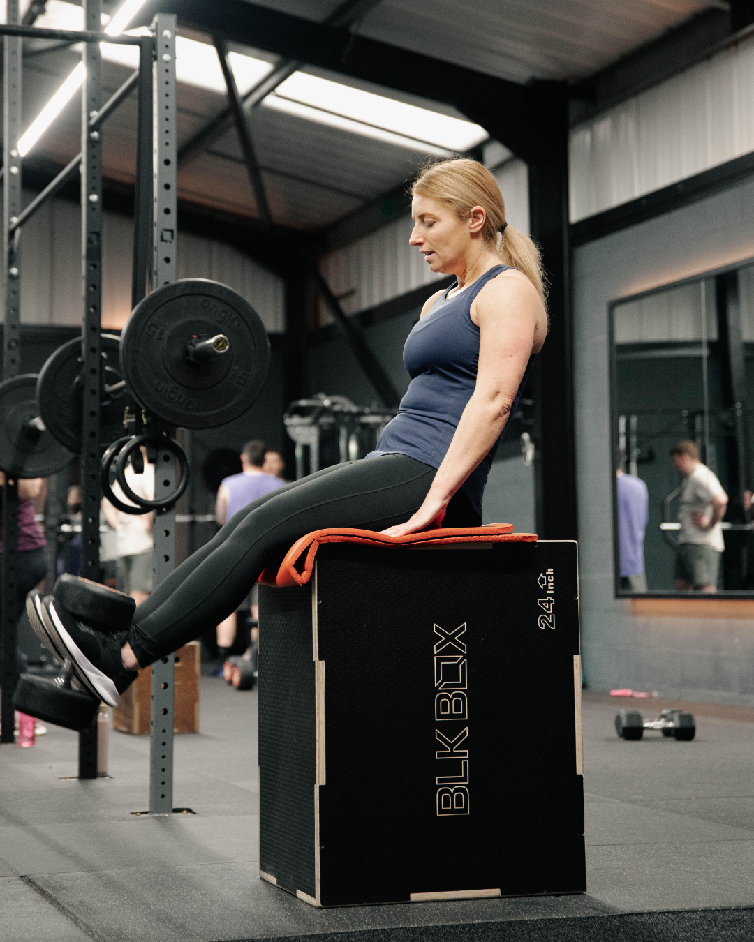 Woman performing leg extensions using high-quality gym equipment in a modern Gateshead fitness facility during a coached strength workout