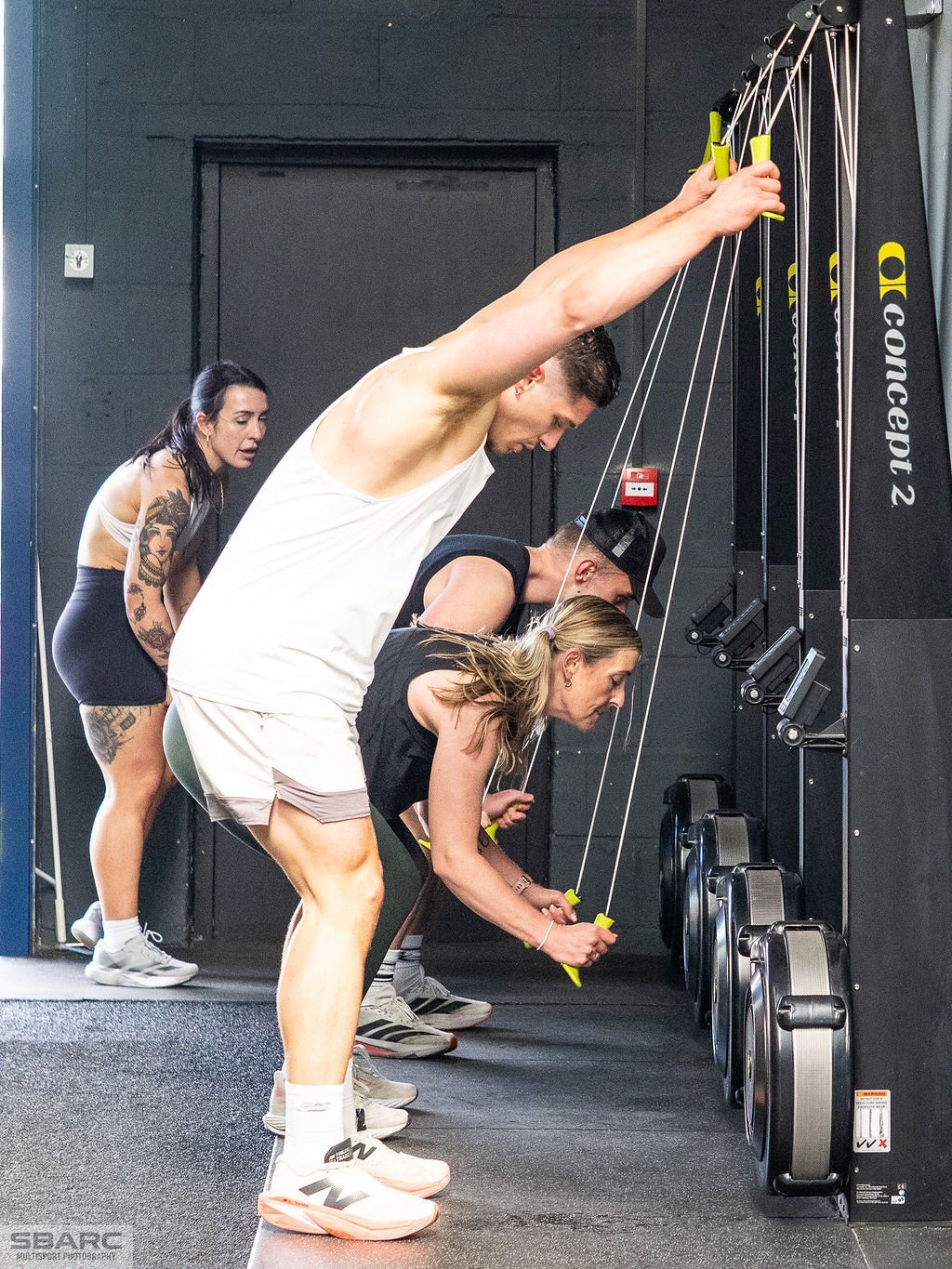 People pushing hard on the 1000m SkiErg during a HYROX-style training event at a Gateshead gym, taking on a high-energy endurance workout together