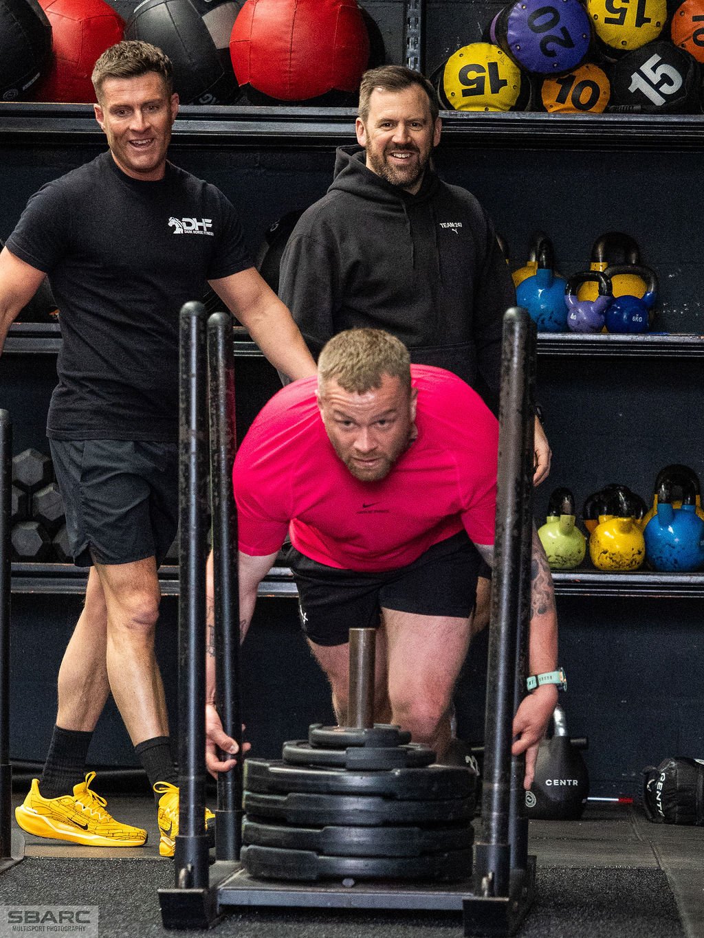 Smiling men taking part in a HYROX-style simulation workout at a Gateshead gym, training together in a motivating and high-energy fitness environment